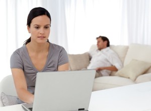 Attentive woman working on the laptop while her boyfriend is sle