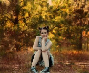 Girl sitting below trees