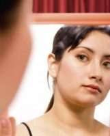 Woman judging herself in the mirror