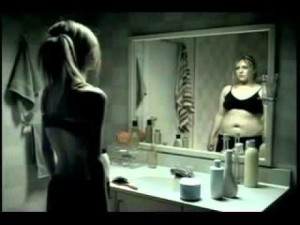 Woman looking at her body in the mirror and dealing with body image concerns