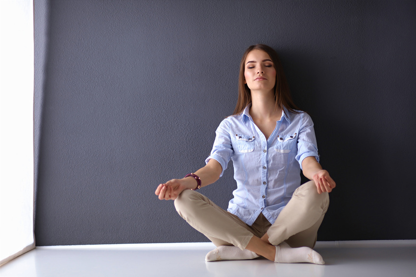 Young woman sitting on the floor doing yoga near wall