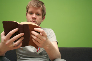 Young man reading small Bible