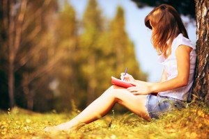 College girl leaning on tree reading a book during COVID-19