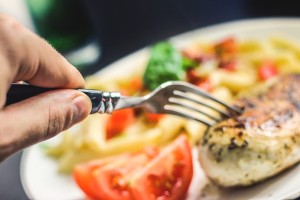 Man sticking fork in brat at meal time