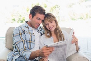Happy couple reading newspaper on couch