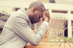 stressed young businessman sitting outside corporate office