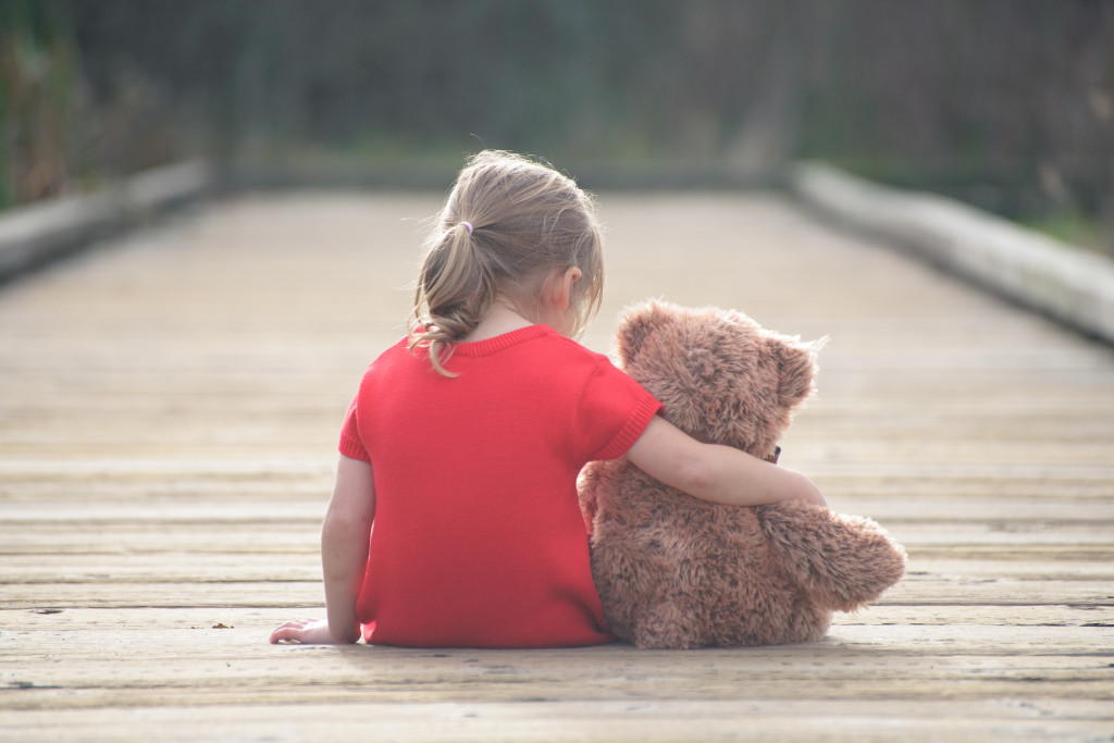 Young girl sitting with her teddy bear after being told about her parents divorce