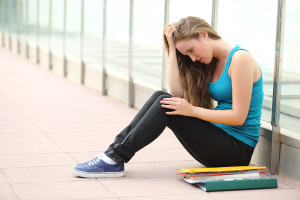 Beautiful teenager girl depressed sitting on the floor outdoor