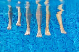 Funny underwater family legs in swimming pool on vacation