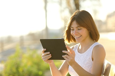Happy woman using a tablet to check her social media accounts