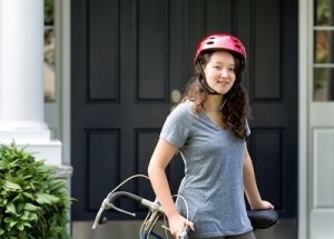 Teenage Girl wearing helmet while resting on bicycle outdoors ne