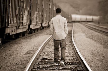 Guy walking on railroad tracks