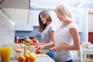 Portrait of happy mother and her daughter cooking and discussing Eating Disorders in Children