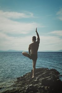 Man doing yoga on the beach