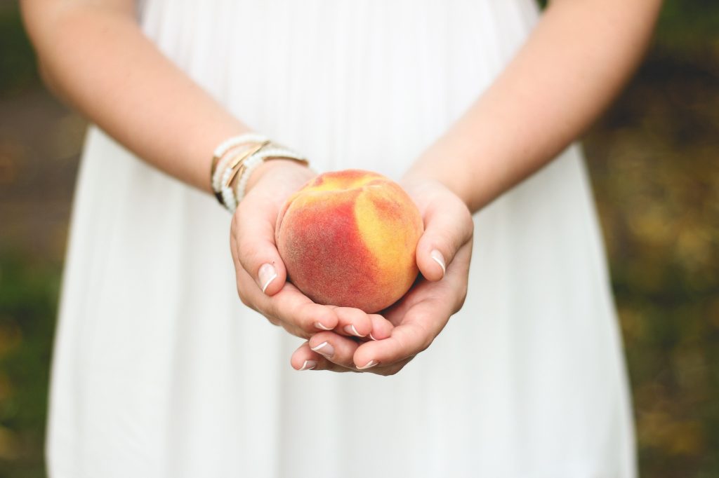 Woman holding a peach trying to not be Anorexic