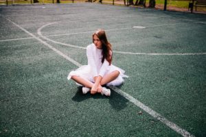 Young woman with ballet attire sitting on the tennis court