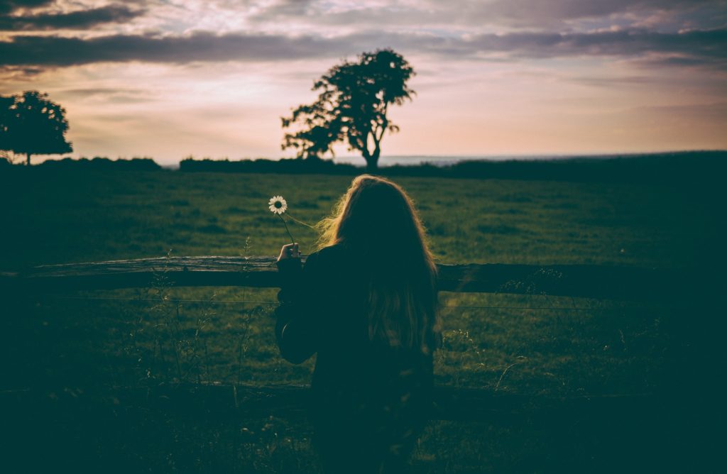 Woman with flower by a fence