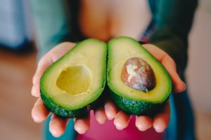 Woman who eats vegan holding an avacado