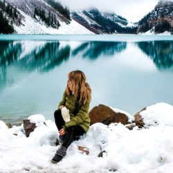 Woman sitting down next to a lake