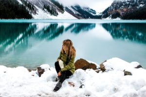 Woman sitting down next to a lake