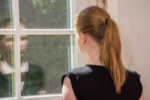 Teen girl staring out a window thinking about bulimia