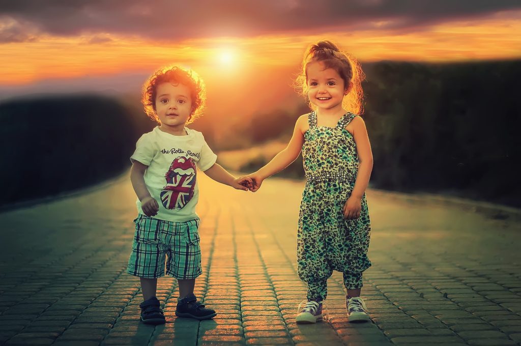 Two Children holding hands on a brick path