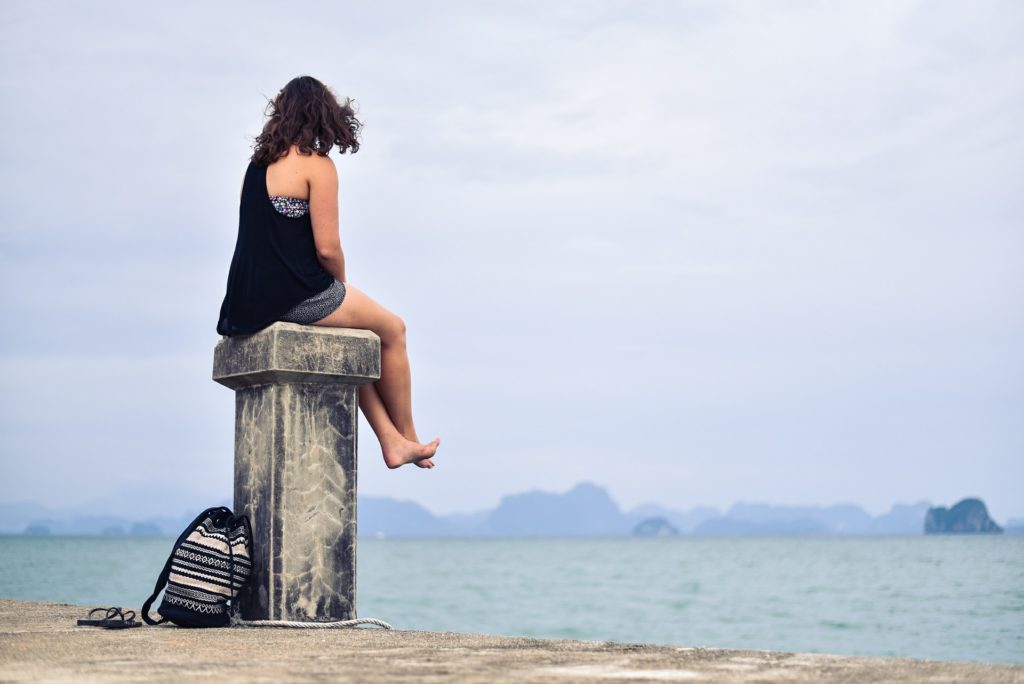 Person sitting on a stone pillar