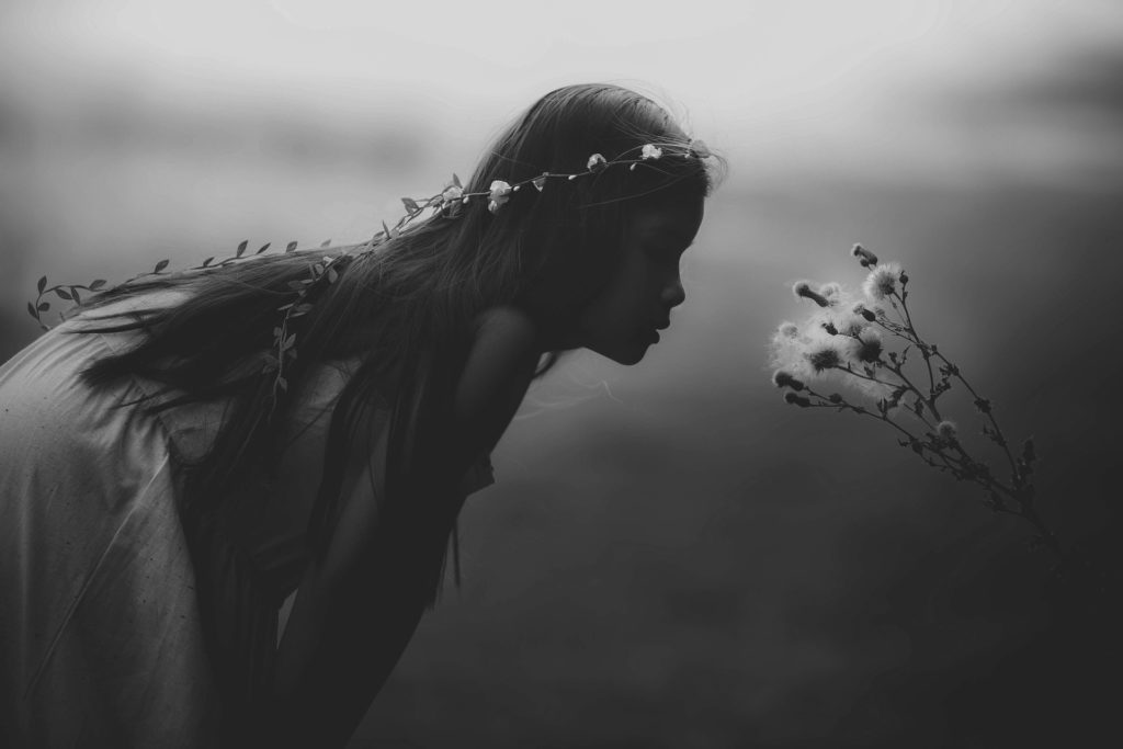 Young girl using Mindfulness Skills in Eating Disorder Recovery and smelling a flower