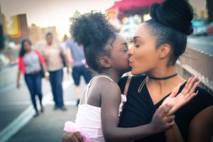 African-American lady kissing her daughter after overcoming summer eating disorder triggers