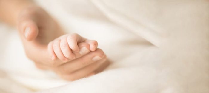 Mom holding newborn hand