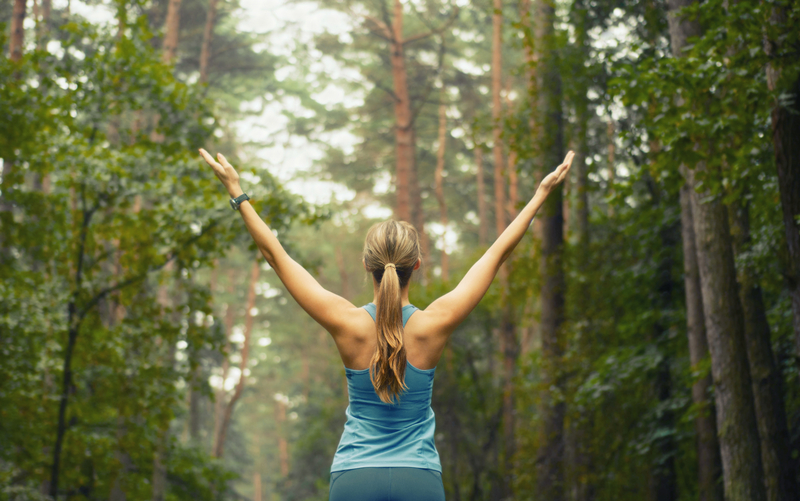 woman in the woods with hands up