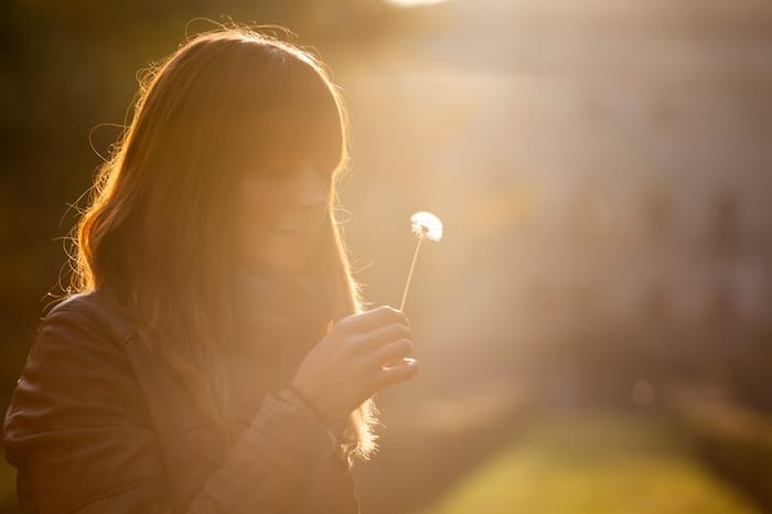 woman in sunset holding a dandelion