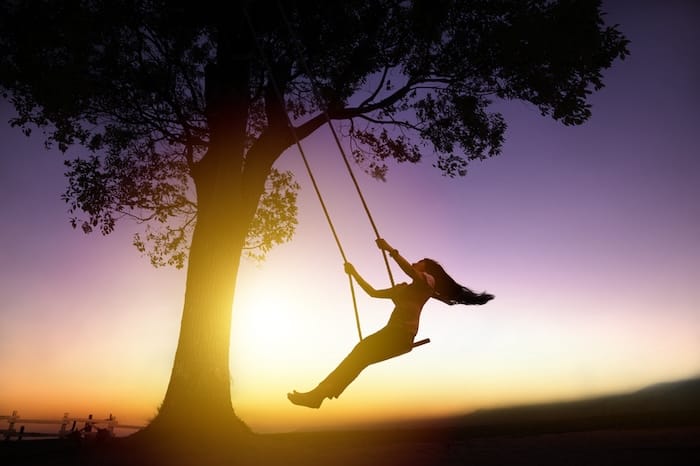 woman on a tree swing at sunset