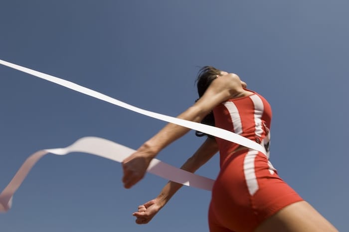 female runner crossing finish line tape