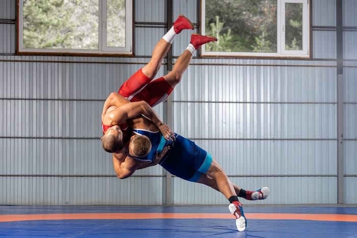 one male wrestlers on a wrestling mat throwing another